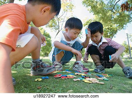 Stock Photo - grinning, holding, squatting, casual, children's wear. Fotosearch