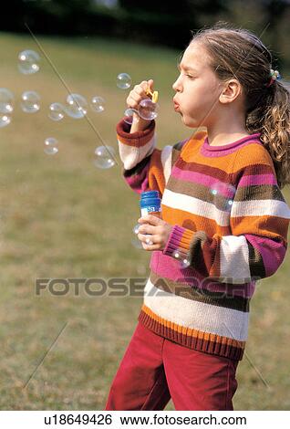 Girl blowing bubbles outside View Large Photo Image Stock Photograph - Girl blowing bubbles outside . Fotosearch