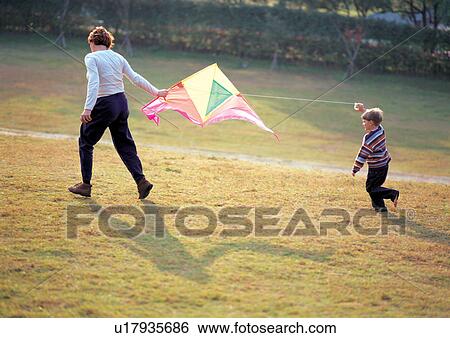 Stock Photograph - Mother and son playing with a kite . Fotosearch