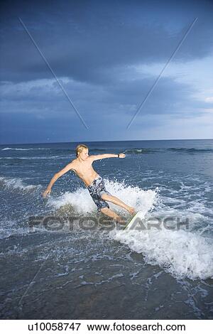 Stock Photo - Caucasian male teen riding skimboard.. Fotosearch