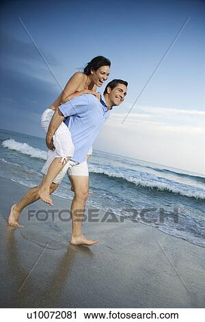 Caucasian mid-adult male carrying female piggyback style on beach. View Large Photo Image Stock Image - Caucasian mid-adult male carrying female piggyback style on beach.. Fotosearch