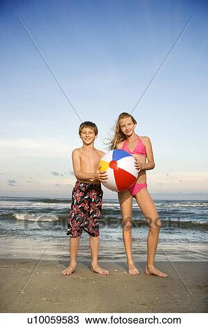 Caucasian pre-teen boy and girl holding beachball on beach. View Large Photo Image Stock Image - Caucasian pre-teen boy and girl holding beachball on beach.. Fotosearch