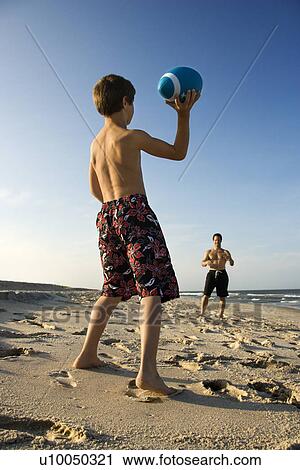 Stock Image - Caucasian pre-teen boy throwing football to mid-adult male.. Fotosearch