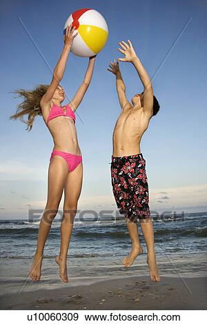 Caucasian pre-teen girl and boy playing with beachball on beach. View Large Photo Image Stock Photo - Caucasian pre-teen girl and boy playing with beachball on beach.. Fotosearch