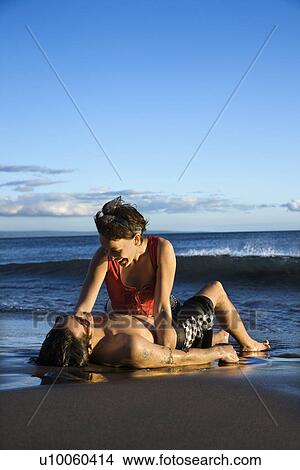 Caucasian young adult couple frolicking on beach. View Large Photo Image Picture - Caucasian young adult couple frolicking on beach.. Fotosearch