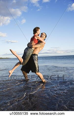 Stock Photography - Caucasian young adult couple frolicking on beach.. Fotosearch