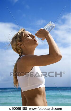 Caucasian young adult woman drinking water on beach. View Large Photo Image Stock Photo - Caucasian young adult woman drinking water on beach.. Fotosearch