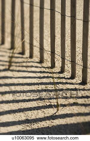 Stock Photography - Close-up of fence and shadows on beach on Bald Head Island, North Carolina.. Fotosearch