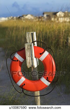 Stock Image - Life preserver hanging on post on beach.. Fotosearch