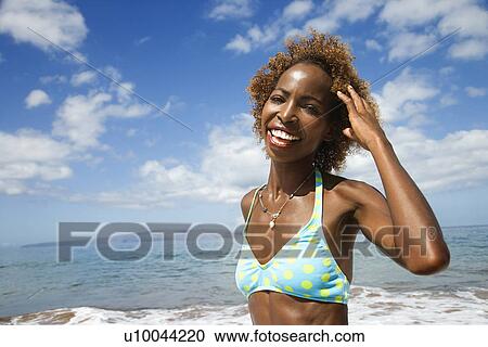 Mid-adult Black female smiling and touhing hair with ocean in background. View Large Photo Image Stock Image - Mid-adult Black female smiling and touhing hair with ocean in background.. Fotosearch