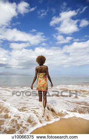 Stock Photography - MId-adult Black female walking towards ocean.. Fotosearch