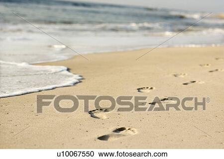 Stock Image - Scenic sandy coastline with footprints and waves.. Fotosearch