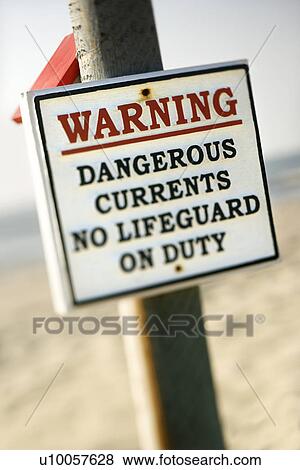 Warning sign on post at the beach with ocean in background. View Large Photo Image Stock Photo - Warning sign on post at the beach with ocean in background.. Fotosearch