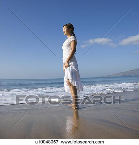Young Asian female standing at shoreline. View Large Photo Image Stock Photo - Young Asian female standing at shoreline.. Fotosearch