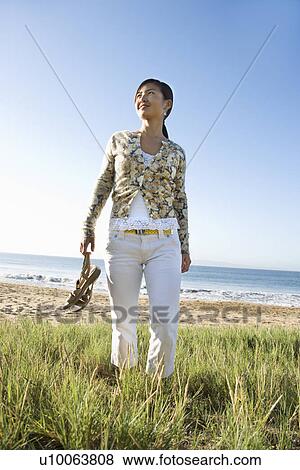 Young Asian female walking down beach carrying sandals. View Large Photo Image Stock Photo - Young Asian female walking down beach carrying sandals.. Fotosearch