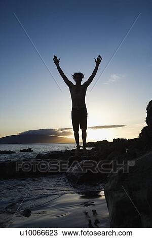 Stock Image - Young Caucasian male adult jumping on beach.. Fotosearch