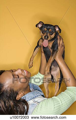 African American young adult female holding Miniature Pinscher dog. View Large Photo Image Stock Image - African American young adult female holding Miniature Pinscher dog.. Fotosearch