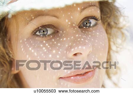 Stock Image - Close-up of young adult female Caucasian with shadow pattern from hat on face.. Fotosearch