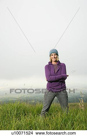 Middle-aged Caucasian woman smiling standing alone in field. View Large Photo Image Picture - Middle-aged Caucasian woman smiling standing alone in field.. Fotosearch