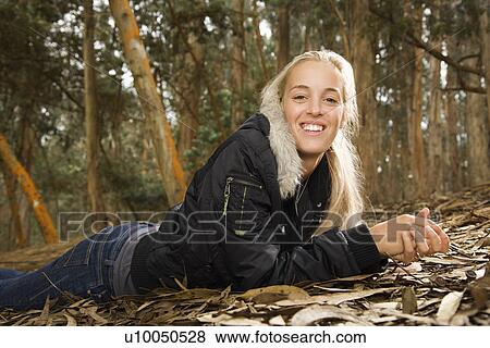 Smiling young adult Caucasian woman lying on ground in forest. View Large Photo Image Stock Photo - Smiling young adult Caucasian woman lying on ground in forest.. Fotosearch