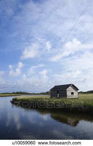 Stock Image - Weathered building in marsh on creek.. Fotosearch