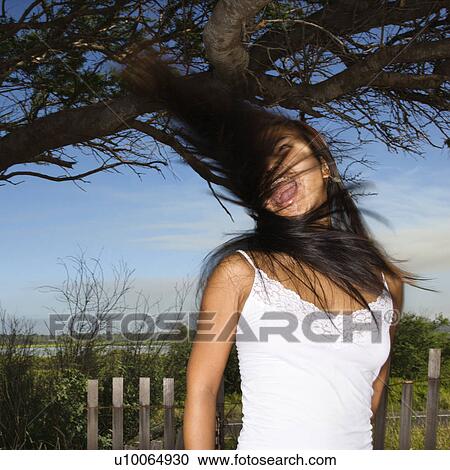 Stock Image - Young adult Asian female screaming and swinging her hair.. Fotosearch