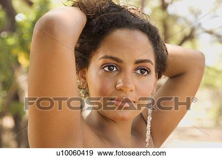 Young-adult Black woman with arms behind head holding hair up. View Large Photo Image Stock Photo - Young-adult Black woman with arms behind head holding hair up. . Fotosearch