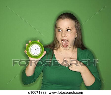 Young female Caucasian adult holding and pointing to clock. View Large Photo Image Stock Image - Young female Caucasian adult holding and pointing to clock.. Fotosearch