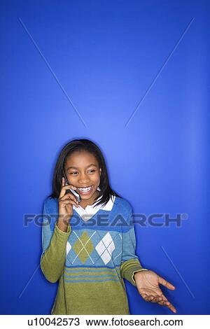 Portrait of African-American teen girl smiling and talking on cellphone standing in front of blue background. View Large Photo Image Stock Image - Portrait of African-American teen girl smiling and talking on cellphone standing in front of blue background.. Fotosearch