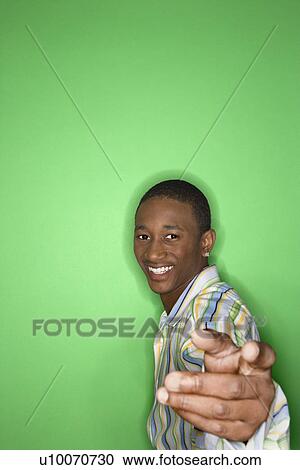 Portrait of smiling African-American teen boy holding hand out toward viewer against green background. View Large Photo Image Stock Image - Portrait of smiling African-American teen boy holding hand out toward viewer against green background.. Fotosearch