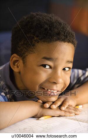 Portrait of young smiling boy with head on hands with book in front looking at viewer. View Large Photo Image Picture - Portrait of young smiling boy with head on hands with book in front looking at viewer.. Fotosearch