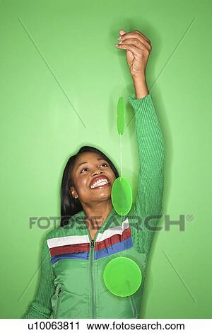 Smiling African-American mid-adult woman in green coat on green background holding green mobile. View Large Photo Image Stock Image - Smiling African-American mid-adult woman in green coat on green background holding green mobile.. Fotosearch