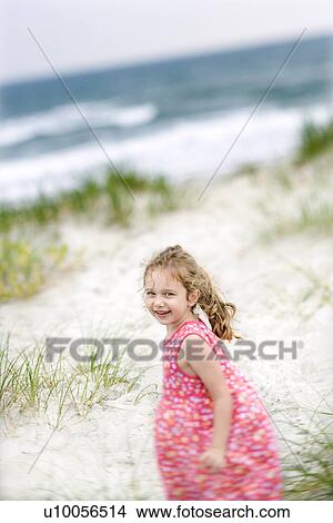 Caucasian female child on beach turning around looking at viewer smiling. View Large Photo Image Picture - Caucasian female child on beach turning around looking at viewer smiling.. Fotosearch
