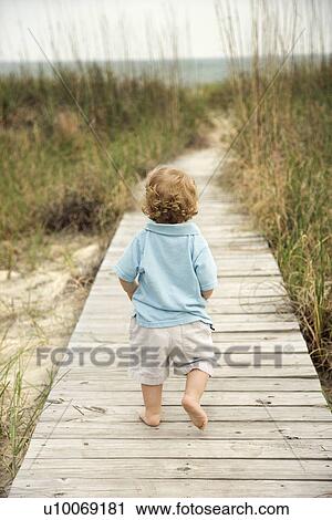 Caucasian male toddler walking on beach access walkway toward beach. View Large Photo Image Stock Image - Caucasian male toddler walking on beach access walkway toward beach.. Fotosearch