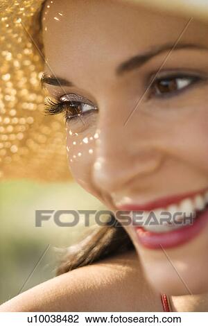 Stock Image - Caucasian mid-adult female close-up wearing straw hat.. Fotosearch