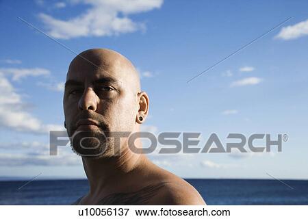 Stock Photo - Caucasian prime adult bald male portrait on beach.. Fotosearch