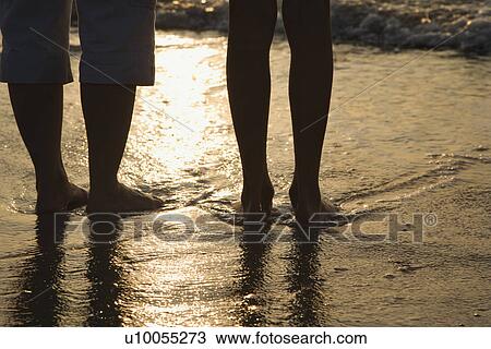 Download Caucasian women standing barefoot on beach in water. Stock Image | u10055273 | Fotosearch