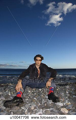 Caucasian young adult male sitting on rocky beach. View Large Photo Image Stock Photograph - Caucasian young adult male sitting on rocky beach.. Fotosearch
