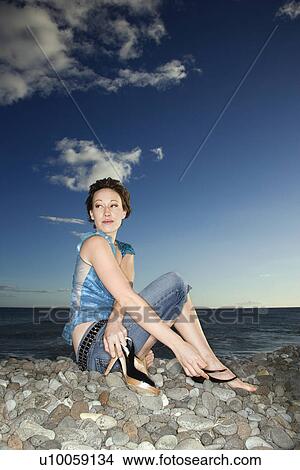 Caucasian young female adult sitting on rocky shore. View Large Photo Image Picture - Caucasian young female adult sitting on rocky shore.. Fotosearch