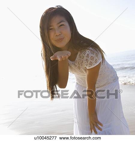 Stock Photo - Young adult Asian female blowing a kiss toward viewer.. Fotosearch