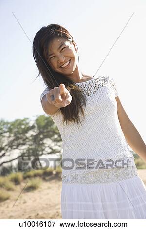 Stock Photo - Young adult Asian female pointing at viewer.. Fotosearch