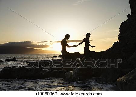 Stock Photo - Young adult Caucasian male and female silhouetted on beach.. Fotosearch