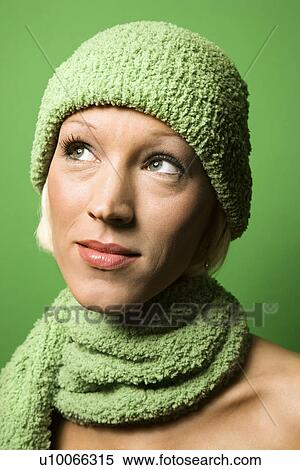 Stock Photography - Head and shoulder portrait of smiling young adult Caucasian woman on green background wearing winter hat and scarf.. Fotosearch