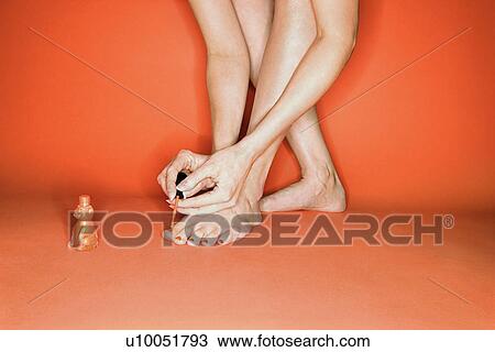 Legs and feet of Caucasian mid-adult woman on orange background painting her toenails with nail polish. View Large Photo Image Stock Image - Legs and feet of Caucasian mid-adult woman on orange background painting her toenails with nail polish.. Fotosearch