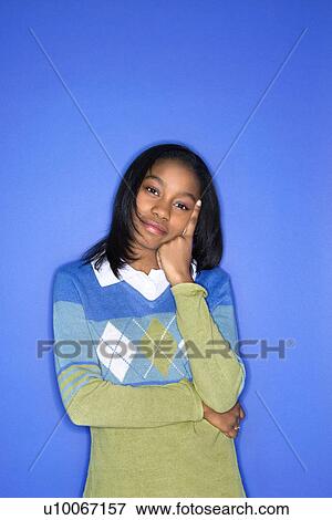 Portrait of African-American teen girl with head on hand standing against blue background. View Large Photo Image Stock Photo - Portrait of African-American teen girl with head on hand standing against blue background.. Fotosearch