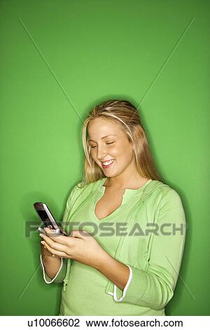 Portrait of blond Caucasian teen girl smiling at cellphone against green background. View Large Photo Image Stock Image - Portrait of blond Caucasian teen girl smiling at cellphone against green background.. Fotosearch