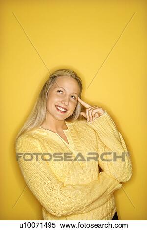Portrait of Caucasian blond teen girl pointing at her head standing against yellow background. View Large Photo Image Stock Photography - Portrait of Caucasian blond teen girl pointing at her head standing against yellow background.. Fotosearch
