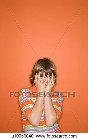 Portrait of Caucasian boy with hands covering his face standing against orange background. View Large Photo Image Stock Photo - Portrait of Caucasian boy with hands covering his face standing against orange background.. Fotosearch