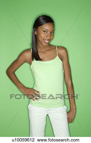 Portrait of smiling African-American teen girl with one hand on hip standing against green background. View Large Photo Image Stock Image - Portrait of smiling African-American teen girl with one hand on hip standing against green background.. Fotosearch