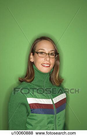Stock Photo - Portrait of smiling young adult Caucasian woman on green background wearing winter coat.. Fotosearch
